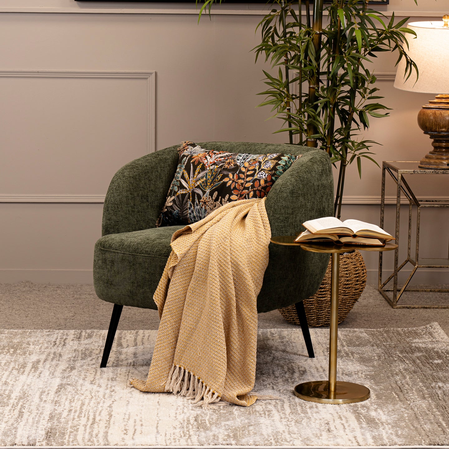 Green armchair with a beige blanket and patterned pillow in a living room setting.